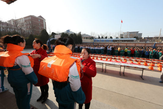 客船服務員向學生演示救生衣穿戴